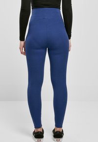 Leggings blu a vita alta realizzati in tessuto elasticizzato, design aderente, texture liscia, con uno stile pulito e minimalista senza pattern visibili.