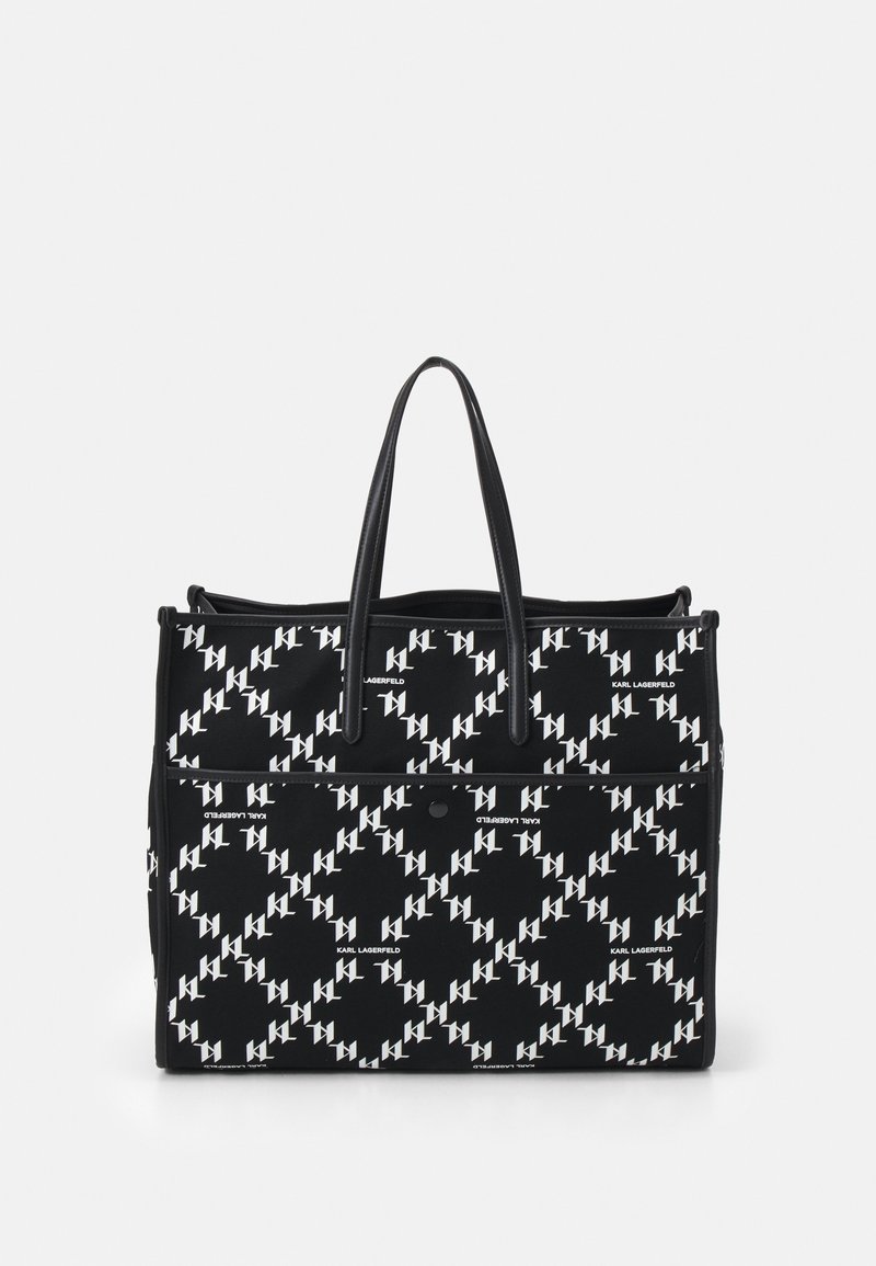 Sac fourre-tout en tissu noir avec un motif de logo blanc répétitif. Il est doté de deux poignées robustes et d'une poche avant zippée.