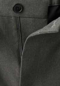 Siva tkaninska jakna z gladko teksturo, ki ima črn gumb in zadrgo ob sprednjem odpiranje. Čiste, natančno krojene linije.