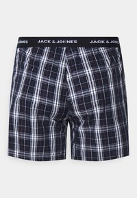 Boxers de hombre en patrón de cuadros azul marino, con acentos en blanco y rojo. Fabricados con una tela ligera y cuentan con una cintura elástica.