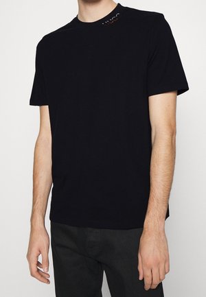 Black cotton t-shirt with short sleeves, featuring a round neckline and red accent rivets at the shoulder. It has a casual fit.