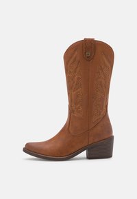 Botte de cowboy en cuir marron avec bout pointu, motif de feuilles brodé, tige haute et talon empilé. Texture lisse avec surpiqûres accentuées.