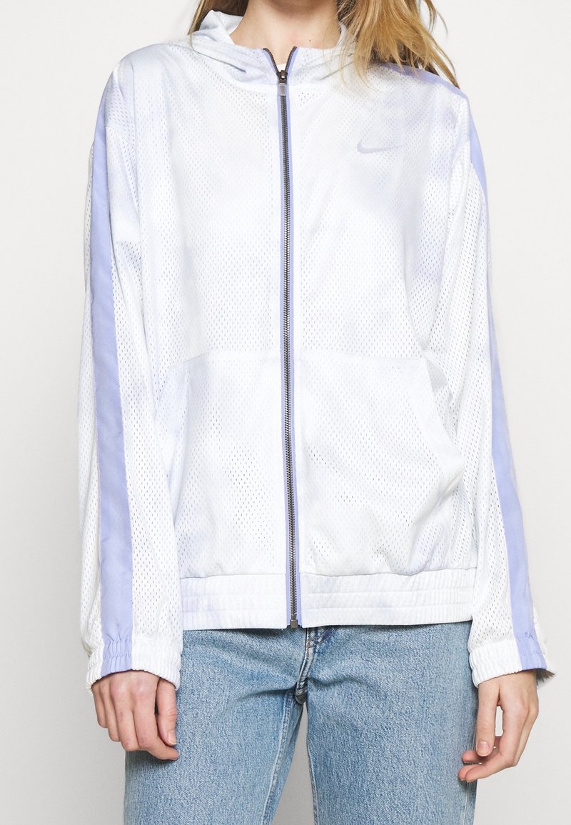 Bílo-šedá síťovaná bunda s fialovými akcenty, plně zipová přední část, kapuce a elastické manžety. Obsahuje kapsy a má prodyšnou texturu.