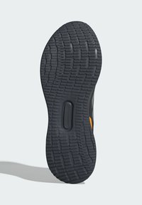 Schwarze Gummisneakersohle mit einem detaillierten Profil. Mit einem orangefarbenen Akzent und einer runden Einsenkung für zusätzlichen Grip und Flexibilität.