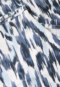 Modrá a bílá látka se vzorem s abstraktním designem v podobě štětcových tahů; měkká textura; obsahuje různé odstíny modré a světle modré akcenty.