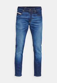 Vaqueros de mezclilla azul con corte ajustado, que presentan un diseño de cinco bolsillos, costuras en contraste y un ligero desgaste en los paneles frontales.