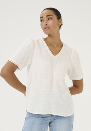 White cotton blouse with short puff sleeves, V-neckline, textured fabric, and lace trim detailing around the neckline and sleeves.