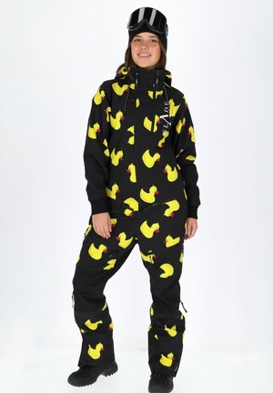 Black ski suit featuring repeated yellow rubber duck patterns, zippers, and adjustable cuffs, designed for warmth and mobility.