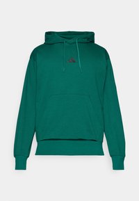 Hoodie vert en tissu doux, avec une poche avant, des cordons de serrage et un petit logo noir à trois bandes sur la poitrine.