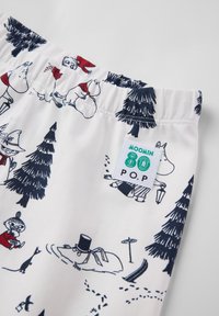 White cotton shorts featuring a Moomin character print in navy blue, with elastic waistband and a sewn-on logo tag.