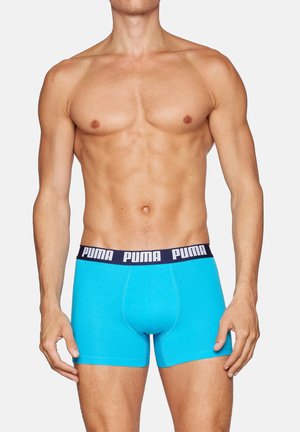 Türkisfarbene Boxershorts mit einem marineblauen Bund, der weiße "PUMA"-Beschriftungen aufweist. Hergestellt aus dehnbarem Stoff bieten sie eine figurbetonte Passform.