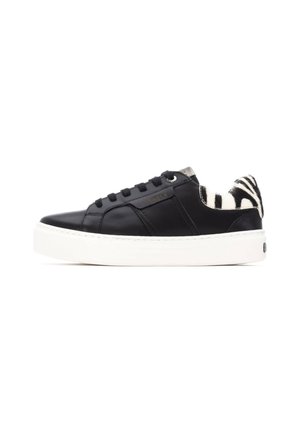 Zapatilla de cuero negra con suela de goma blanca, que presenta un acento de piel de estampado de cebra en el talón y cordones negros planos.