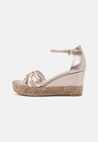 Metallic rosa Keilsandaletten mit geflochterer Jutesohle, ausgestattet mit überkreuzten Riemen und verstellbarem Knöchelriemen. Glatte Textur mit glänzenden Akzenten.