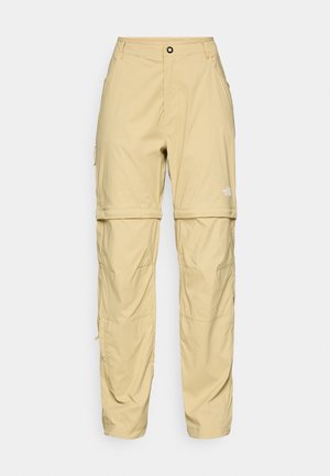 Beige cargobukser laget av lett stoff, med glidelåslommer, knappelukking og en logo på høyre lår.