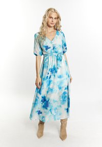 Abito maxi in tessuto leggero e fluido con motivo ad acquerello blu, scollatura a V e maniche a sbuffo, cinchato in vita con una cintura.