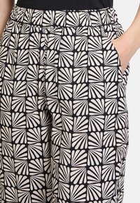 Czarno-kremowe spodnie w wzór liści, z elastycznym pasem i bocznymi kieszeniami dla funkcjonalności.