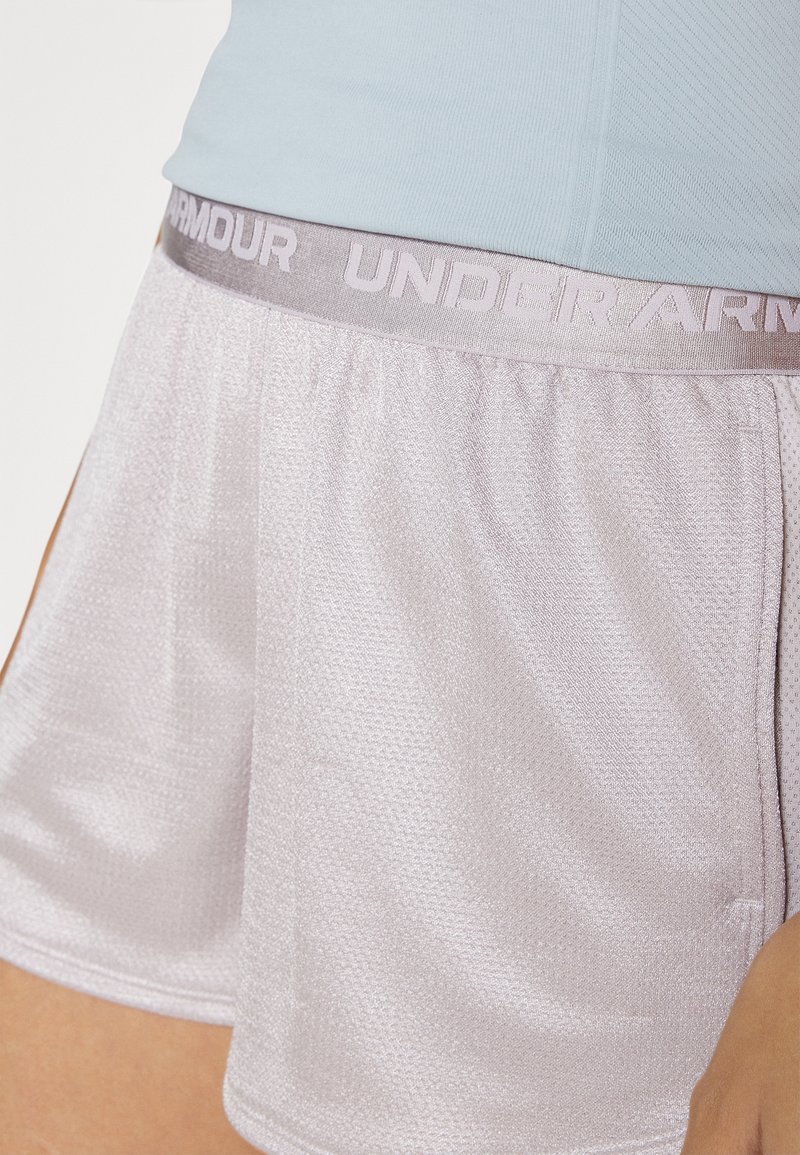 Helle lilafarbene Sportshorts aus atmungsaktivem Mesh-Material, mit einem elastischen Bund, der das „UNDER ARMOUR“-Logo in hellgrau trägt.