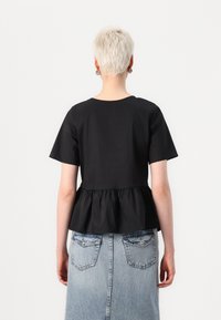 Svart bomull peplum topp med korte ermer, rund halslinning og samlet nederkant, kombinert med en lys blå denimskjørt med baklommer.