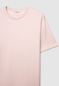 T-shirt a maniche corte di colore rosa chiaro in morbido cotone, con scollo rotondo e cuciture pulite; senza motivi o decorazioni visibili.