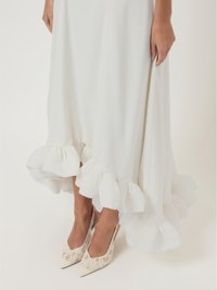 Λευκό φόρεμα με φούστα με βολάν, σε συνδυασμό με ψηλοτάκουνα μποτάκια με λουράκι από δαντέλα και μυτερή μύτη. Η απαλή ύφανση κρέμεται κομψά, αναδεικνύοντας τη σιλουέτα.