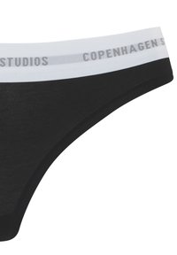 Black cotton thong with a white waistband featuring printed “Copenhagen Studios” in gray. Smooth texture, minimalistic design, and fitted shape.