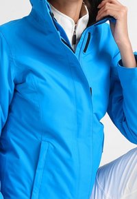 Helle blaue wasserdichte Jacke mit hohem Kragen, Reißverschluss vorne und verstellbaren Manschetten. Glatte Textur, taillierter Schnitt und minimale Akzente.