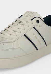 Λευκό χαμηλό sneaker με λεπτομέρειες σε ναυτικό μπλε, λογότυπο "Tommy Jeans" στο πλάι και στη γλώσσα, λευκά κορδόνια και απλή λαστιχένια σόλα.