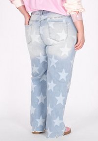 Jeans in denim azzurro chiaro con un motivo a stelle, caratterizzati da un'alta vita, design a cinque tasche e orli sfilacciati.