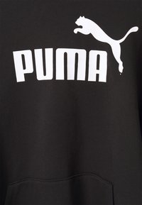 Černá mikina s bílým textem a logem "PUMA". Vzhled zahrnuje kulatý výstřih, dlouhé rukávy a přední kapsu. Měkká textilie.