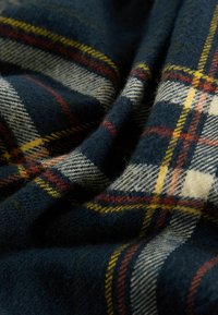 Tweedblandad tyg i mörkblått med ett klassiskt rutmönster. Har gula, röda och vita linjer, mjuk textur och en draperad look.