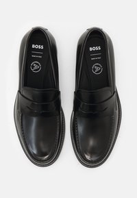 Melnas ādas loafers ar gludu apdari, ar noapaļotu purngalu un dekoratīvu joslu augšējā daļā. Ražots Itālijā.