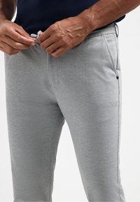 Grijze sportbroek met een gladde textuur, elastische tailleband, koordsluiting, zijzakken en een relaxed fit ontwerp.