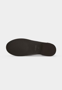 Semelle d'une chaussure femme noire avec grip texturé au talon et à l'avant, taille 38, présentée sur un fond blanc uni.