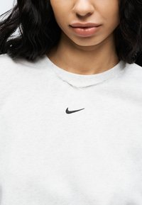 Γκρι φούτερ με στρογγυλή λαιμόκοψη από μαλακό ύφασμα, με μαύρο λογότυπο Nike ραμμένο στο στήθος και διακριτικά φθαρμένο λαιμό.