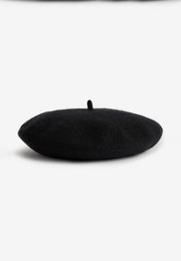 Fekete filc beret, kerek formával, ami a tetején egy kis hurokkal rendelkezik, sima, puha textúrával. Nincsenek minták vagy díszítések.