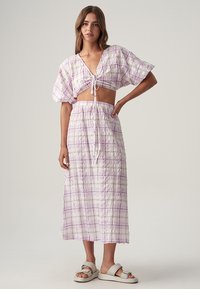 Tvådelad outfit med en kortärmad puffärmad topp och en lång kjol, båda i ett rutigt mönster av ljuslila och vitt. Tyg av strukturerad bomull.
