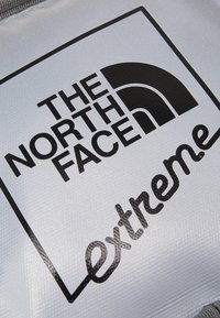 Prodotto argento con superficie testurizzata caratterizzato da un grande logo nero che recita "THE NORTH FACE" e dalla parola "Extreme" in un carattere stilizzato.