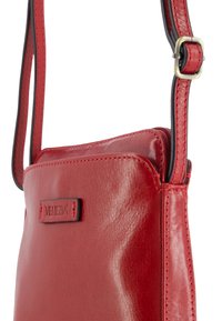 Red leather crossbody bag with a smooth texture, featuring a zip closure and a black-accented strap. Brand logo displayed on the front.