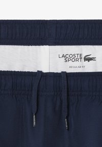 Marineblauwe shorts met elastische tailleband, touwtjes en witte binnenvoering. Gekenmerkt door Lacoste Sport branding en een regular fit ontwerp.