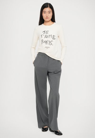 Long-sleeve cream top with “JE T’AIME PARIS” printed in black, paired with grey wide-leg trousers, featuring a smooth texture and elastic waistband.