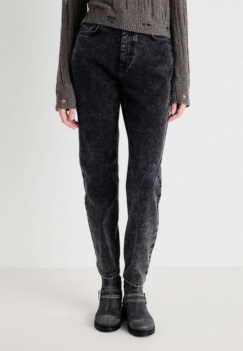 Zwarte gewassen denim jeans met een ontspannen pasvorm, voorzien van subtiele vervaging, vijf zakken en een rechte pijp. Ggedragen met grijze enkellaarsjes.