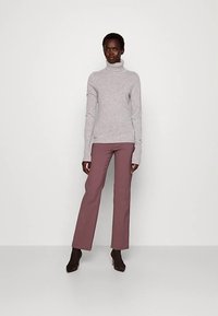 Világosszürke, puha anyagból készült garbó, hozzáillő, testhezálló mályvaszínű nadrággal. Az öltözék karcsú sziluettet és hosszú ujjakat mutat.