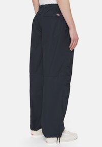 Granatowe spodnie cargo z elastycznym paskiem, dwoma tylnymi kieszeniami i mankietami ze sznurkiem, wykonane z lekkiej tkaniny.