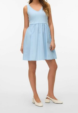 Jasnoniebieska sukienka bez rękawów z dekoltem w serek, marszczoną talią i rozkloszowanym dołem. Do tego kremowe buty na słupku.