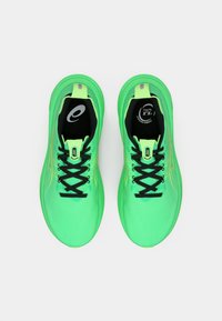 Ténis de corrida verde néon com um upper em malha respirável, atacadores pretos e subtis acentos amarelos. Sola almofadada e estrutura de suporte.