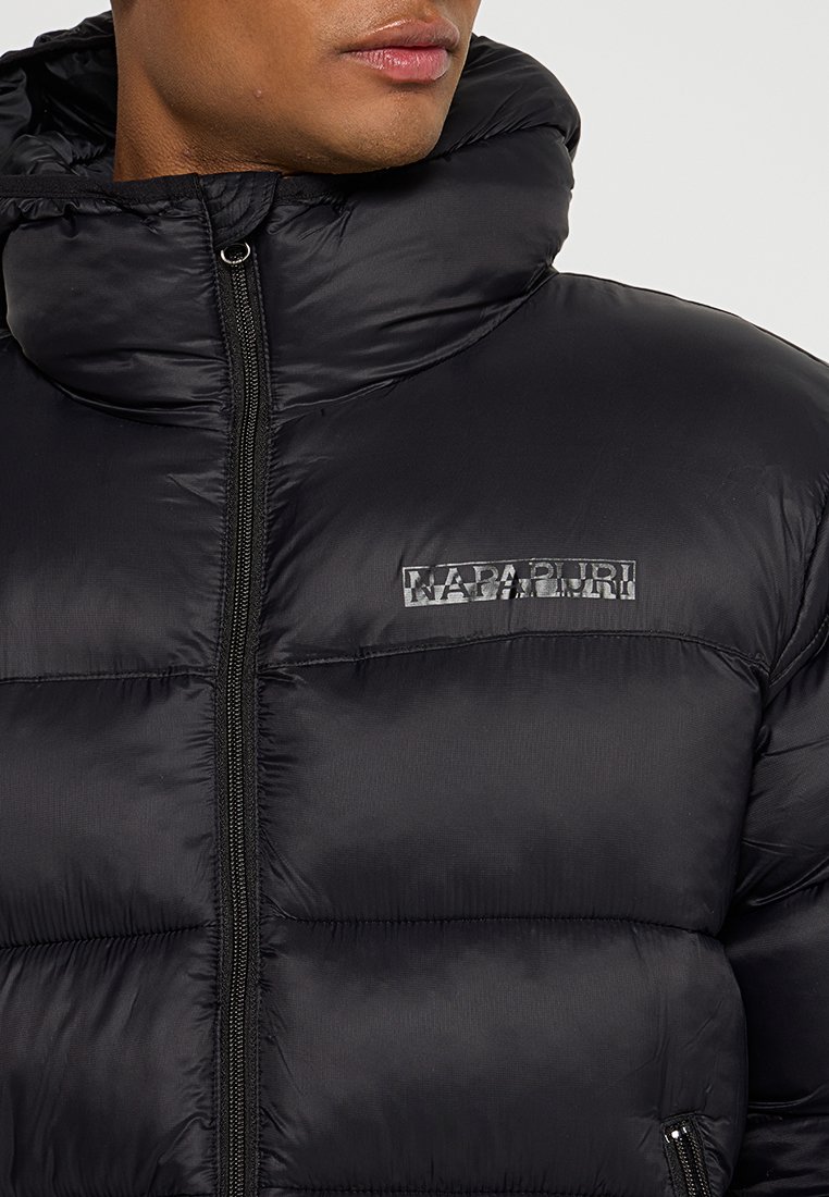 Doudoune noire avec un col haut, finition brillante, texture matelassée, fermeture éclair à l'avant et un logo réfléchissant sur la poitrine gauche.