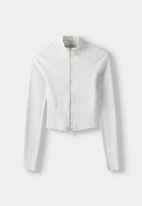 Vit, ribbad kort jacka med långa ärmar, dragkedja framtill och ståkrage. Tyget verkar texturerat och mjukt.