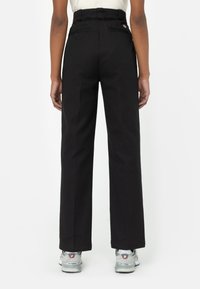 Pantalones de pierna ancha negros con cintura alta, que cuentan con dos bolsillos traseros y un detalle de logotipo bordado. Están hechos de una tela resistente con una textura suave.