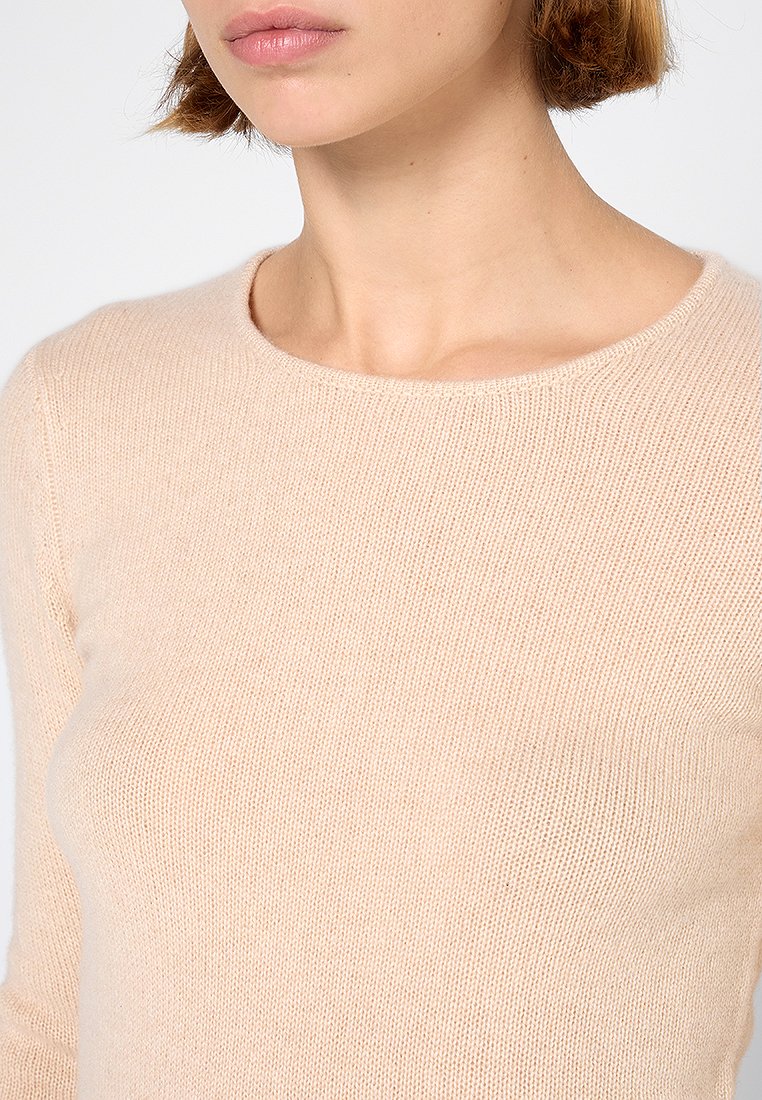 Helles beiges Strickpullover mit rundem Ausschnitt und weicher Textur, der eine figurbetonte Silhouette und ein dezentes Muster im Stoff aufweist.