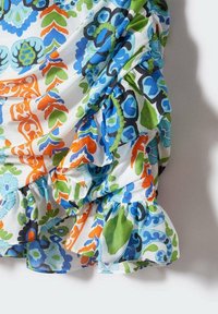 Robe à volants avec un motif floral coloré en bleu, vert, orange et blanc. Tissu léger et texturé avec un design fluide et des volants superposés.